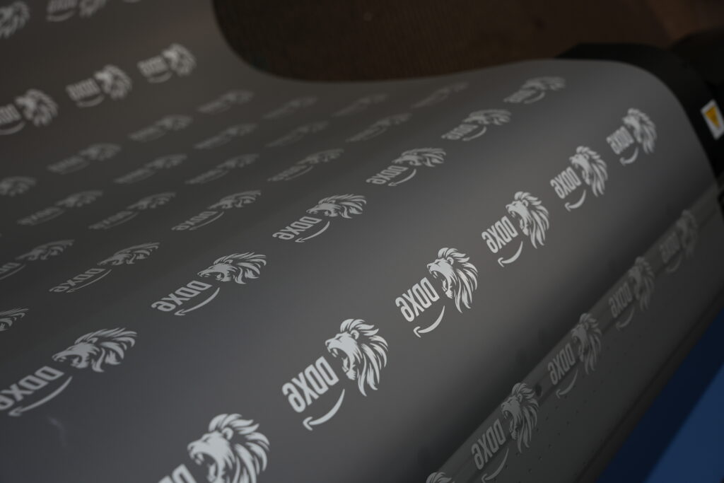 DTF transfer film printed with repeated white logos, ready to be pressed onto garments in Naples, FL