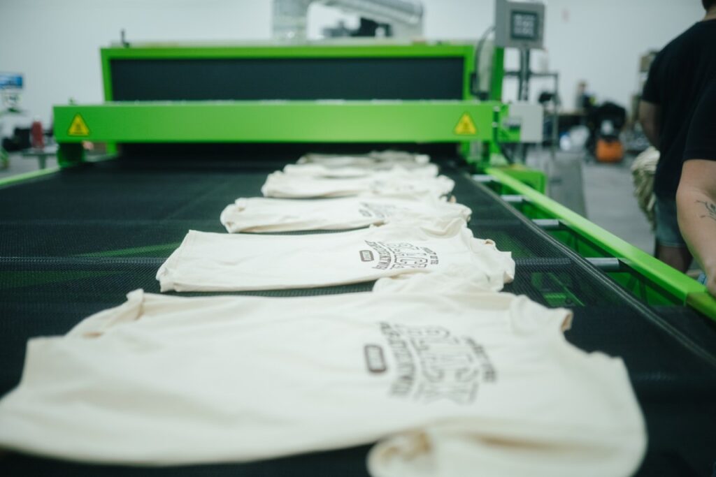 Screen printed shirts moving through the conveyor dryer at the Naples shop